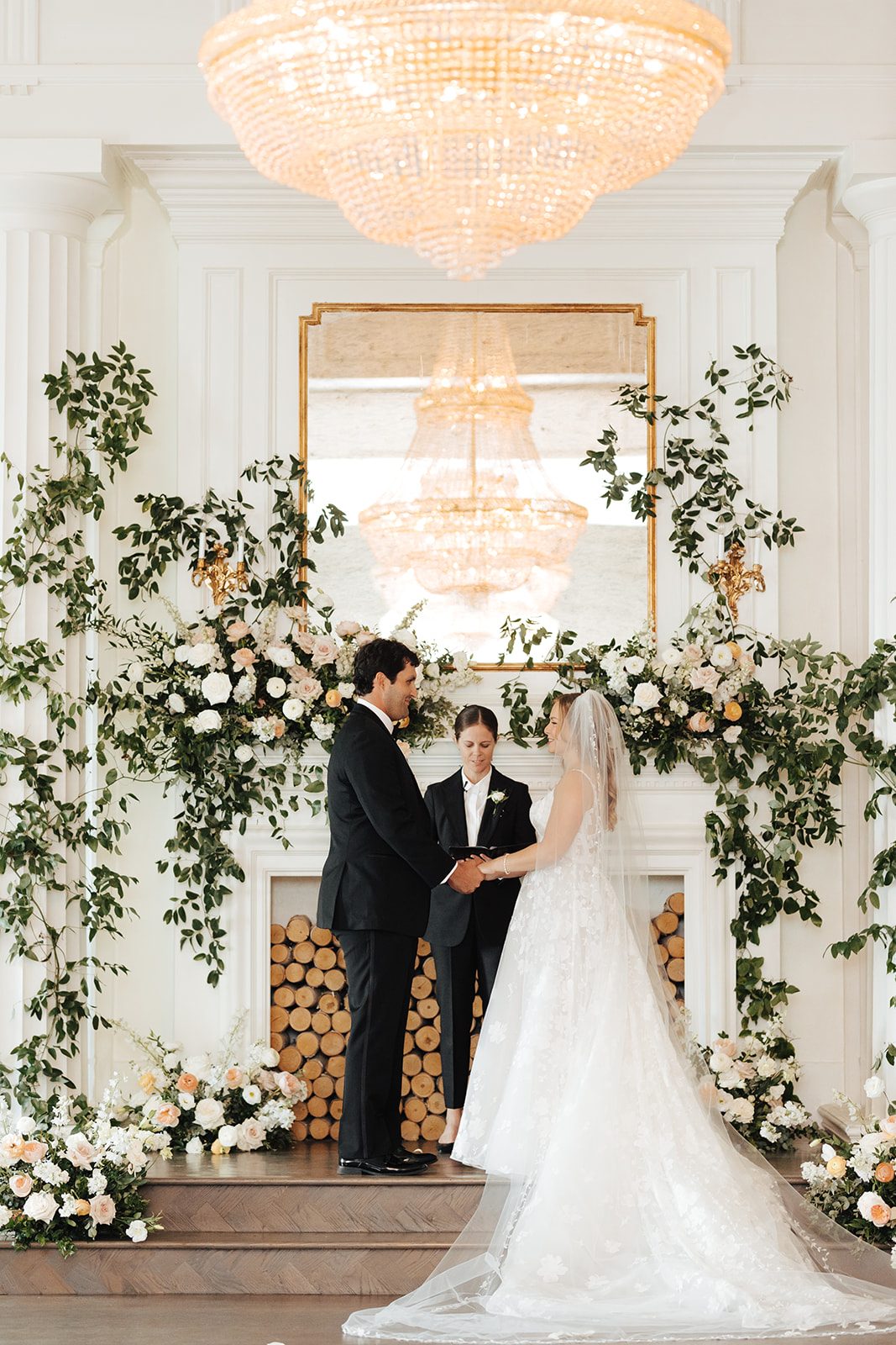 Chelsie officiating a wedding beneath a floral mantle